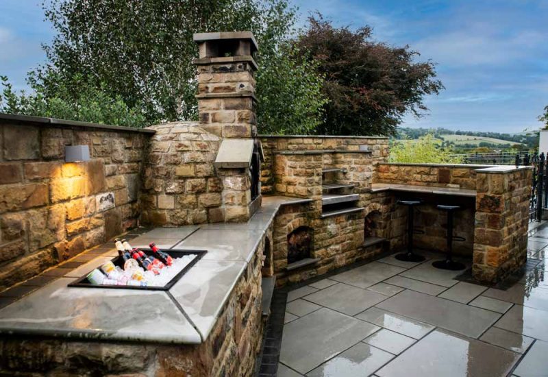 Outdoor kitchen with pizza oven, firepit, sink with beers and breakfast bar.