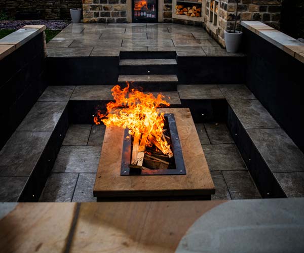 A solid bit of fire comes from a fire pit in a sunken seating area.